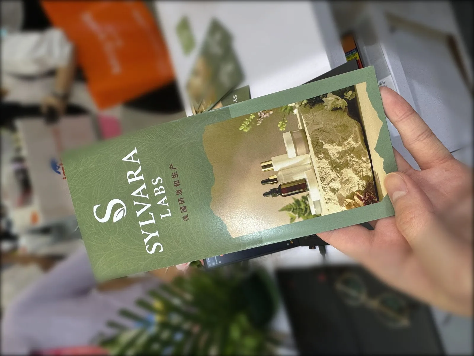 Sylvara Labs brochure held on the show floor, background softened